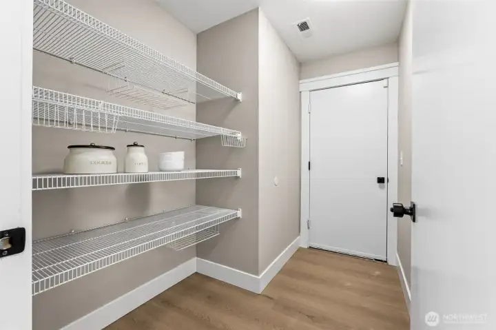 Main level walk-in pantry with connection via closed door to two car garage.
