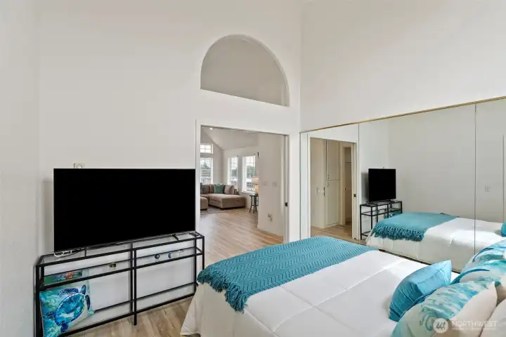 Vaulted primary bedroom, light-filled and mirrored.