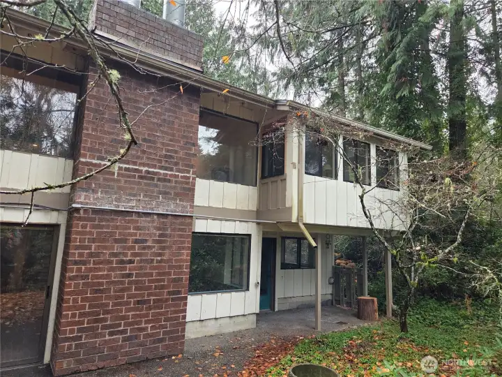 Back side of house opposite of entry. view shows kickout from Primary Bedroom, windows of living room and dining, lower bedroom patio and lower bonus room windows and sliding door.