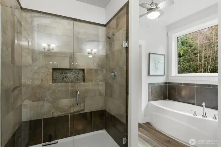 the primary bathroom has a spacious, beautifully tiled shower and a soaking tub. The primary walking closet is accessed through the door next to the tub.
