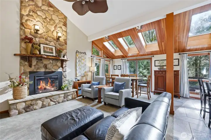 Straight down the entry hall you will enter the open concept living/dining/kitchen spaces complete with vaulted ceilings, wood-wrapped columns/windows/skylights, a river rock electric fireplace, and so much more!