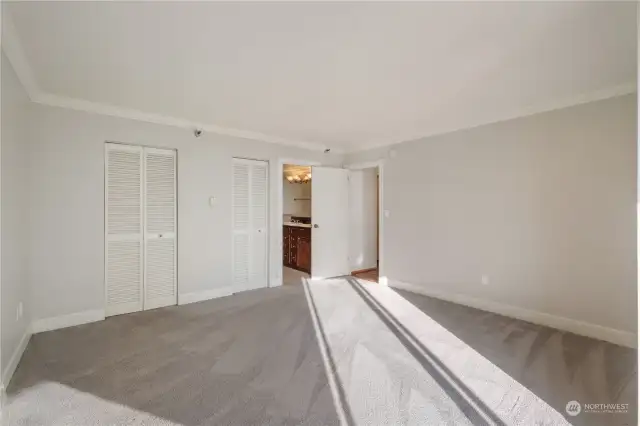 Primary bedroom showing walk in closet and bathroom entrance.