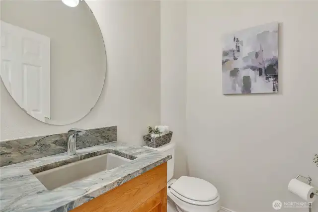 Modernized half bath featuring a stunning stone countertop, seamlessly complemented by the continuation of rich cherry hardwood floors (not shown here) for a cohesive and stylish look.