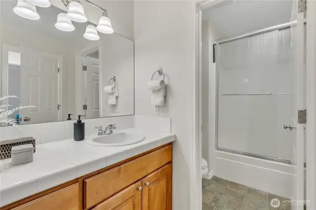 Although not the clearest shot, this main/guest bath impresses with its functionality, offering dual sinks for convenience and a private shower with a water closet for added privacy.