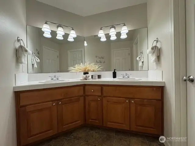 This main/guest bath impresses with its functionality, offering dual sinks for convenience and a private shower with a water closet through the door to the right, for added privacy.