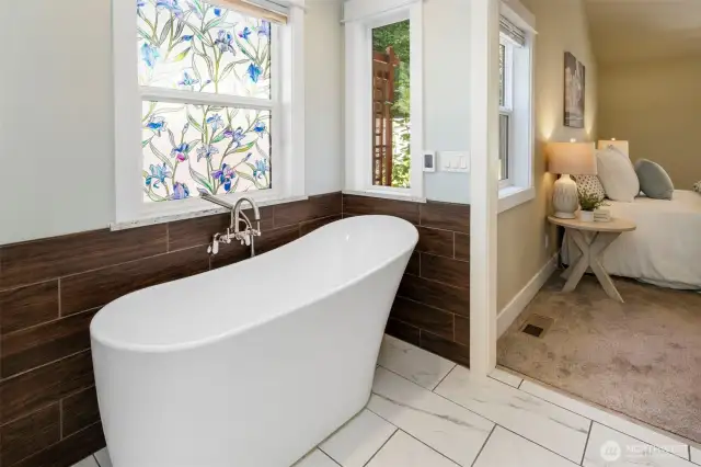 Relax in the freestanding soaking tub set beneath a sunny window—your personal at-home retreat.