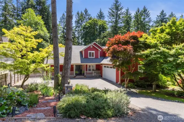 A storybook driveway leads to this vibrant, lovingly maintained home, embraced by mature trees and colorful landscaping.