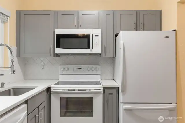 Kitchen with beautiful countertops, tile backsplash, and shaker cabinets.