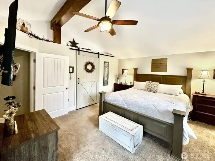 Updated primary with vaulted beamed ceilings, charming barn door leads to updated bath.