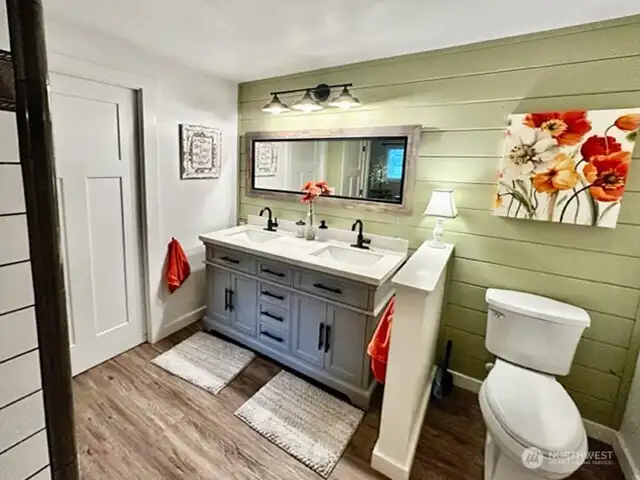Updated primary bath with laminate flooring & sweet accent wall.  Access to walk in closet next to vanityl