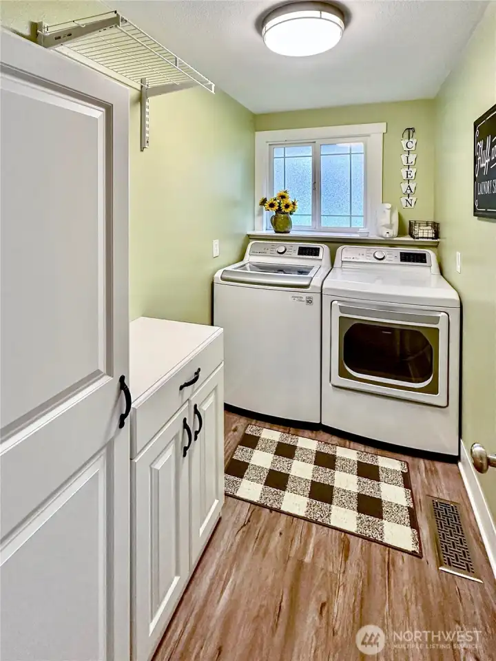 Nice sized laundry with laminate flooring and window.