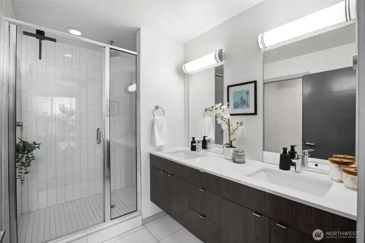 The en-suite bath features a double vanity and a sleek, glass-enclosed shower.