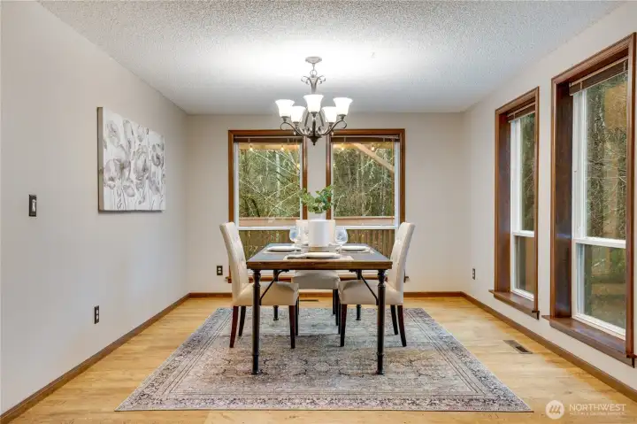 Bright dining room with large picture window and triple side windows, offering wooded views and plenty of space to host family dinners or game night.