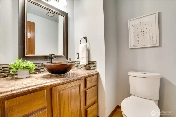 Updated powder room with vessel sink, granite-style counter, and framed mirror—an easy, stylish stop for guests just off the main living areas.