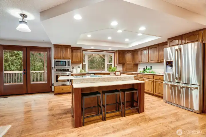 Open-concept kitchen with large center island, bar seating, double doors to the deck, and great flow into the dining and living spaces—built for everyday life and effortless entertaining.