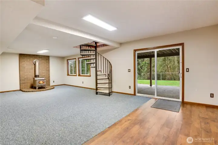 Daylight lower level with pellet stove, circular staircase, and slider to the patio and lawn—great as a media room, play space, or future guest suite.