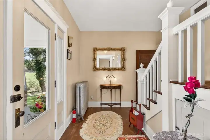 Inside you can immediately feel the history. The entryway welcomes you with hardwood floors and that classic 1890 grandeur. The elegant grand staircase on the right is a perfect match for the vintage details, like the white cast-iron radiator. With light streaming through the glass front door, this foyer offers warmth and charming introduction to this remarkable estate.
