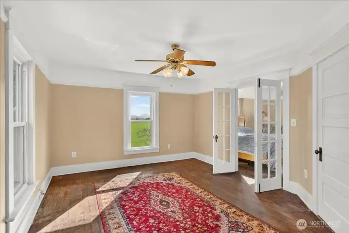 The light in this room gets with windows facing both East and North. It’s the perfect spot to catch the morning sun over the fields. Those French doors are such a great original feature, too—they open right up into the next room, which makes the whole space feel even bigger and more connected.