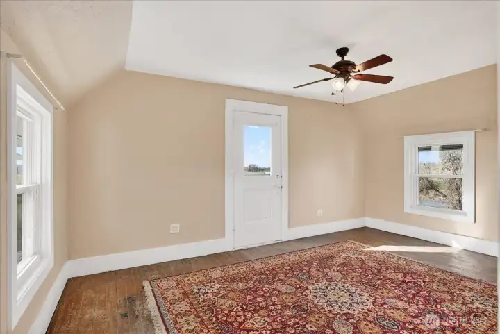 This top floor room is another bright, flexible space with plenty of natural light. You’ve got the same beautiful hardwood floors and classic sloped ceilings that give the upstairs so much character. That door in the center pulls in even more light and looks right out over the property. It’s a great, open spot that could easily work as a home office, a hobby room, or whatever fits your lifestyle.