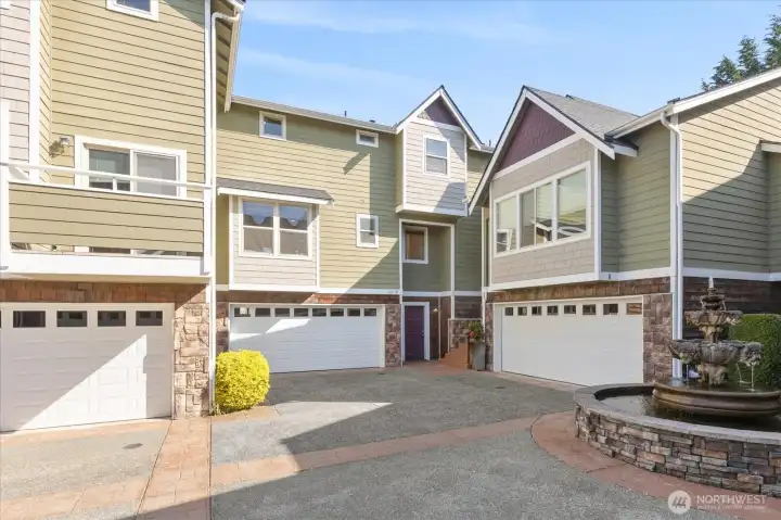 Exterior view of the building showing the garage, entry door, stone accents, and upper-level windows.