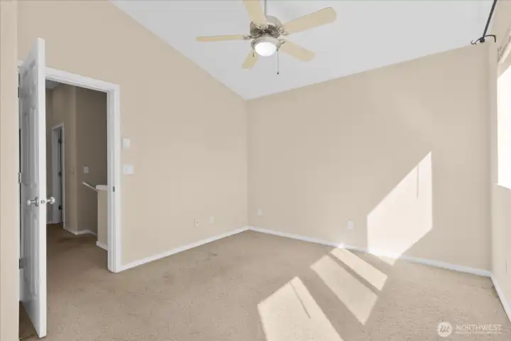 Bedroom with carpeted flooring, ceiling fan, and window allowing natural light.