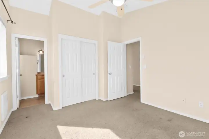 Bedroom with carpeted flooring, ceiling fan, and access to private bathroom.