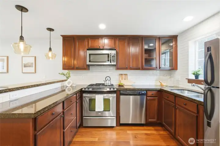 Stainless steel appliances, white subway tile, granite counters and cherry cabinets create a beautiful setting for preparing meals