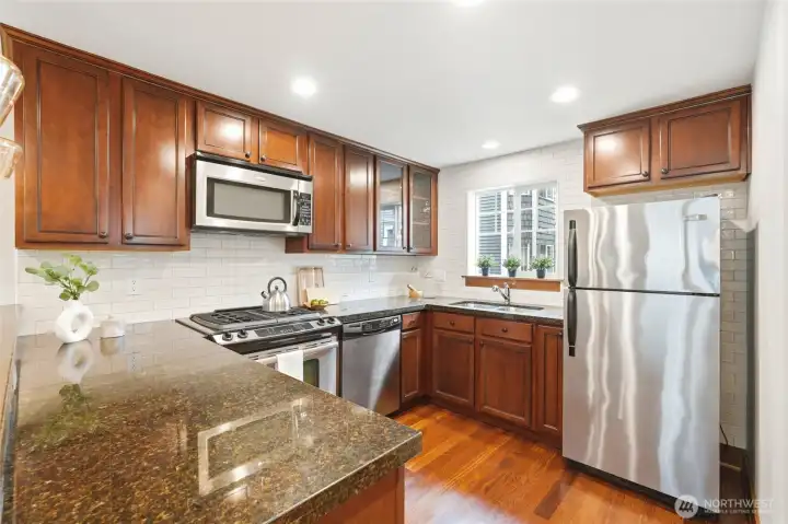 Stainless steel appliances, white subway tile, granite counters and cherry cabinets create a beautiful setting for preparing meals