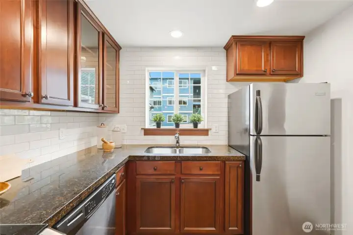 Stainless steel appliances, white subway tile, granite counters and cherry cabinets create a beautiful setting for preparing meals