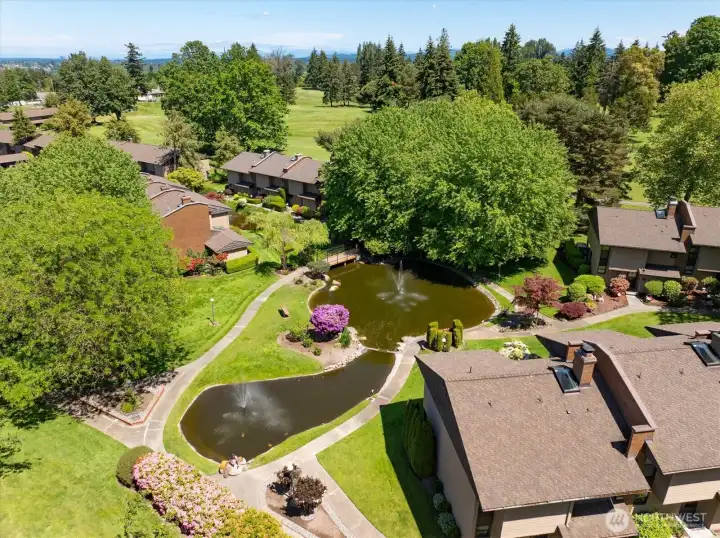 Drone view of the adjacent duck pond with a park-like setting and benches close to the unit.