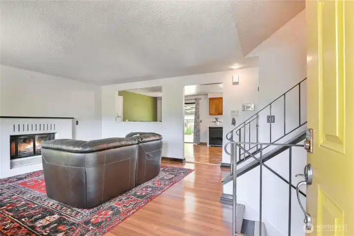 Bright entry with laminate hardwood floors, a brick fireplace, and an open flow to the kitchen.