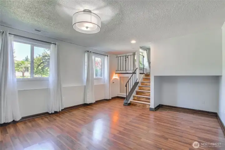 Bright open space with wood-look flooring and staircase to upper level.