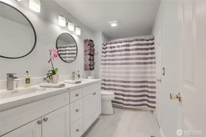 Full bath with a double vanity and tub/shower combo.