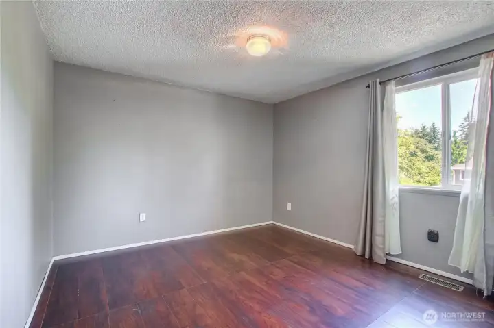 Bright bedroom with laminate flooring and natural light.