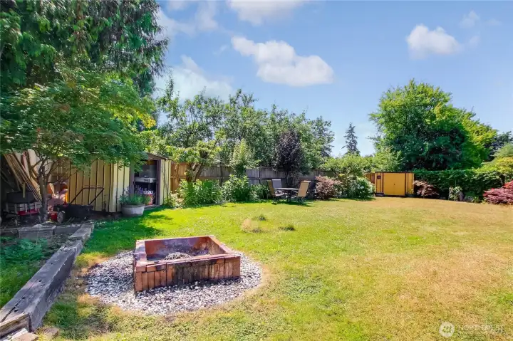 Built-in firepit surrounded by mature landscaping.
