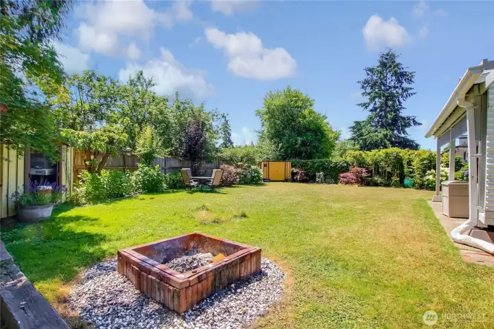 Spacious backyard featuring firepit, patio, and storage shed.