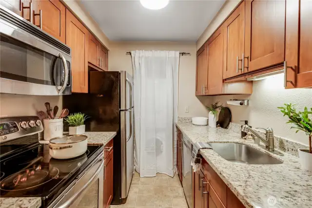 The galley-style kitchen boasts soft-close shaker cabinets, granite countertops, and an undermount sink.