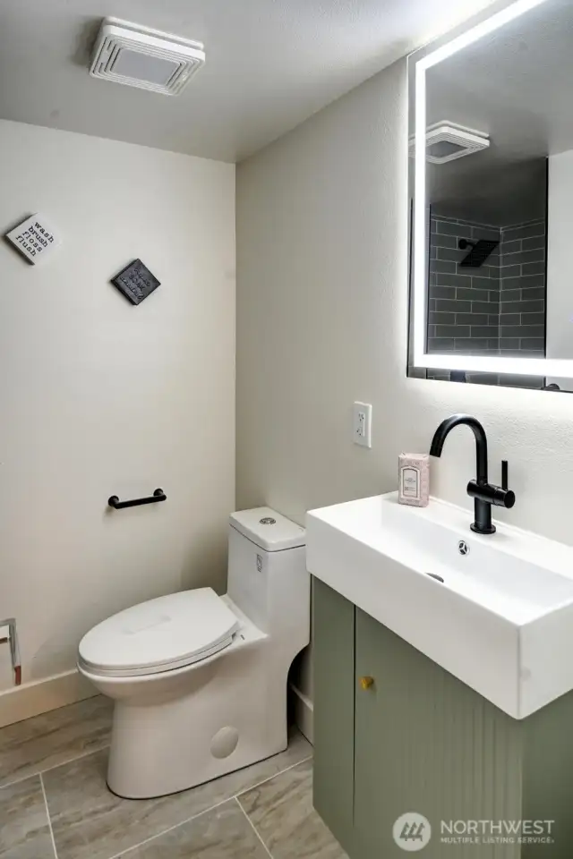 Lower level full bath boasts tile floors and shower plus designer sink and fixtures.