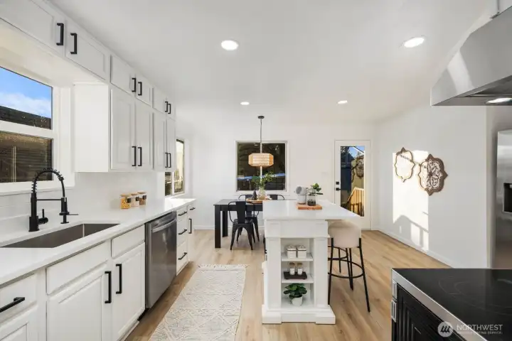 Bright kitchen featuring white cabinetry, quartz countertops, black hardware, and stainless steel appliances for a clean, modern look.
