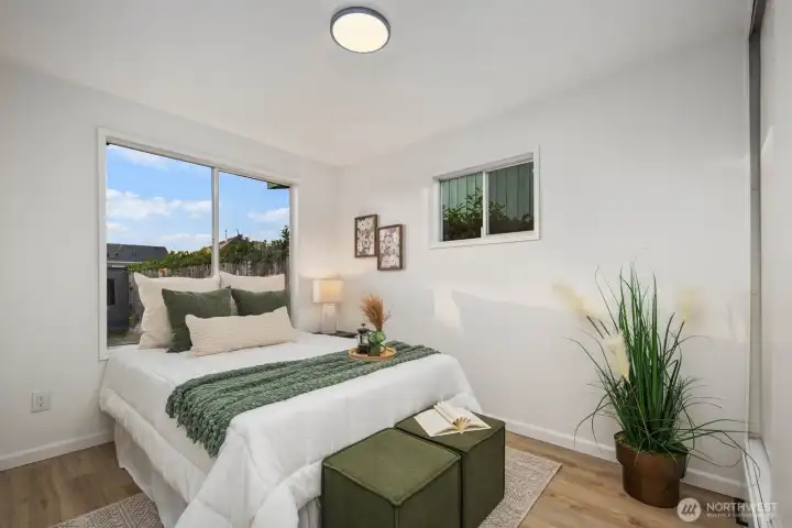 Light-filled bedroom with dual windows, neutral finishes, and a calming palette that complements the wood-look flooring.