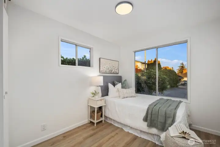 Secondary bedroom with large picture window, modern overhead lighting, and soft natural tones for a serene atmosphere.