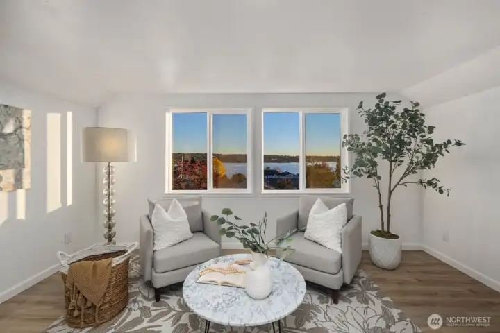 Upper-level sitting area with large windows capturing scenic views and space for a cozy seating arrangement.