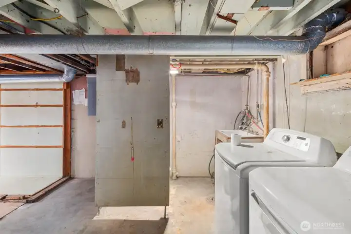 Basement laundry area with washer, dryer, utility sink, and access to mechanical systems.