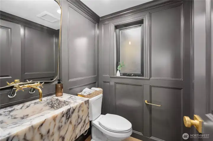 Main level powder room with panache! Complete with a custom stone sink, gold fixtures and custom millwork.