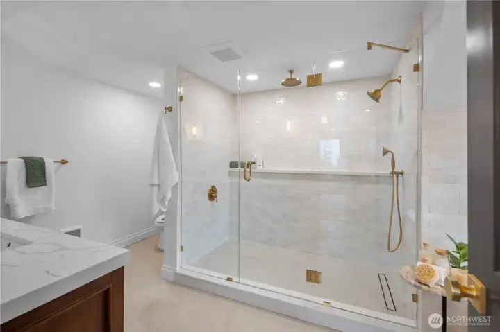 Another view of the Primary en suite bath - showing off the huge shower, gold fixtures, frameless glass enclosure and enviable full-length shelf!