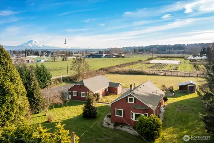 This elevated view captures the property’s exceptional setting, with wide-open farmland stretching out toward a dramatic Mount Rainier backdrop. The flat, productive land and neighboring farms reinforce the agricultural character of the area, offering a rare sense of openness, scale, and connection to the surrounding landscape.