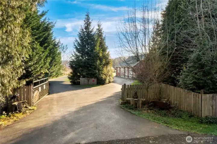 The circular asphalt driveway creates a graceful approach to the property, framed by mature evergreens that provide privacy and a sense of arrival. This drive offers easy access, generous parking, and a natural buffer from the road, reinforcing the peaceful, tucked-away feel of the setting.