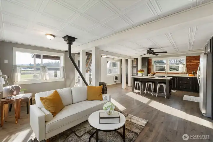 An open-concept layout connects the living area and updated kitchen, creating a space that feels both expansive and inviting. The kitchen features quartz countertops, stainless steel appliances, and an large island, all set against a backdrop of abundant natural light and Mount Rainier views.