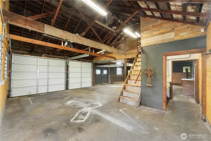 A large detached garage with an open layout, exposed beams, and a solid concrete pad accented with cedar runners. Updated electrical, new insulation, and bright 4-foot LED lighting create a comfortable, functional space suited for vehicles, equipment, and hands-on projects.