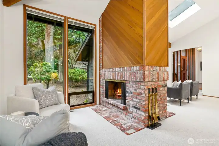 The dramatic double-sided fireplace anchors the space, creating a cozy focal point between the living and gathering areas.